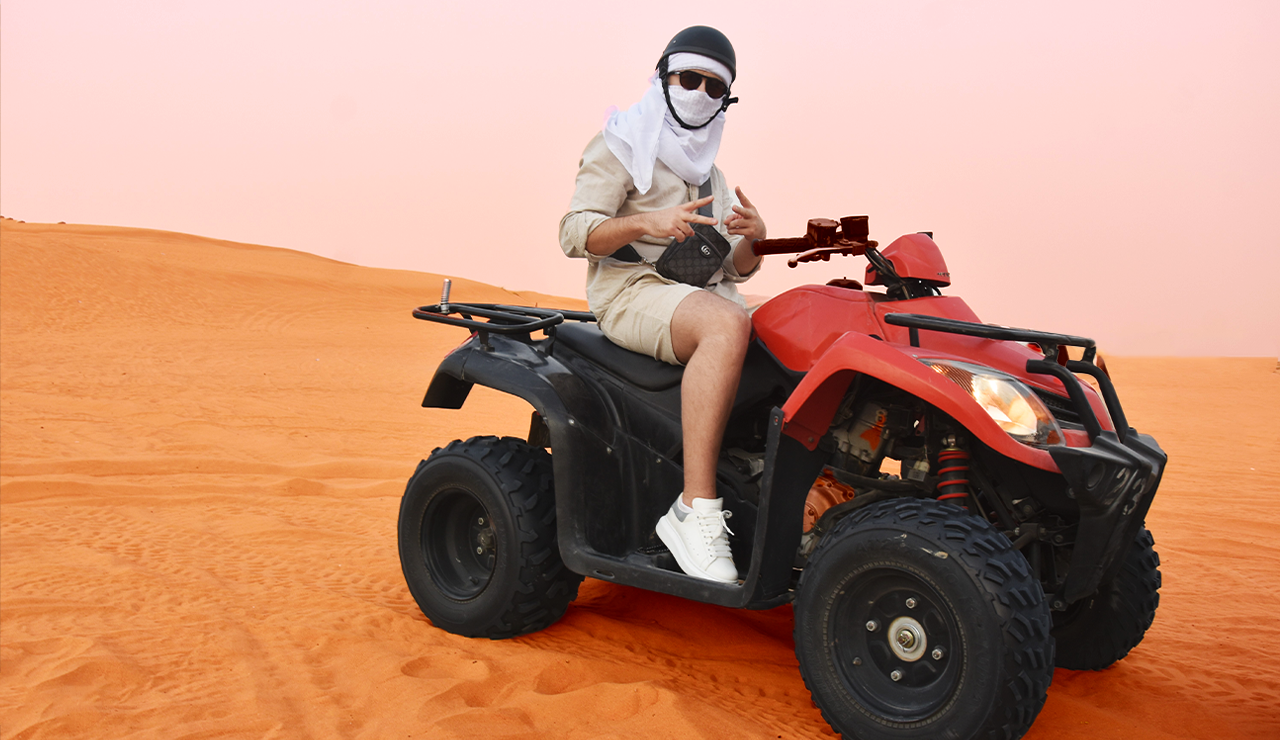 Riders on a quad bike in the Dubai desert wearing safety gear